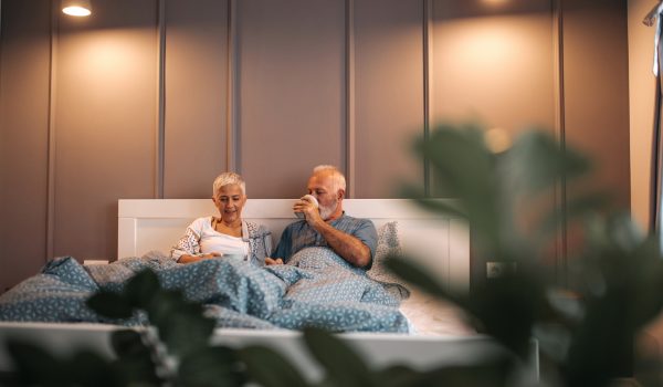 Senior couple drinking morning coffee in bed.