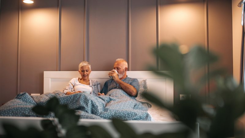 Senior couple drinking morning coffee in bed.