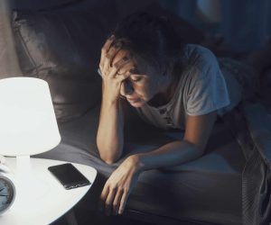 Desperate young woman awake late at night, she can't sleep and she has a bad headache, insomnia and stress concept