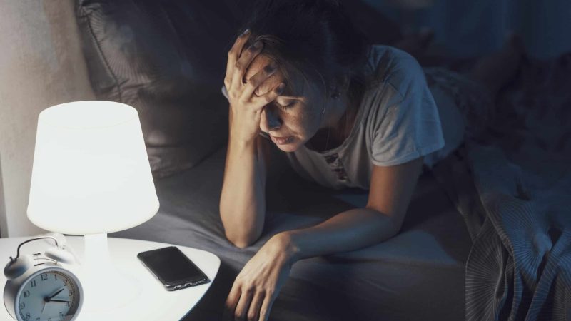 Desperate young woman awake late at night, she can't sleep and she has a bad headache, insomnia and stress concept