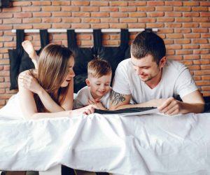 Cute family at home. Mother and father have fun with they little son. Little boy reads book