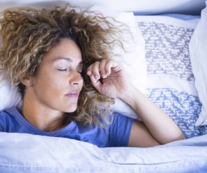 Relax and sleep concept with beautiful caucasian woman sleeping in the morning light at home or hotel - relaxed people in the bed - white pillows and sheet - new day life concept