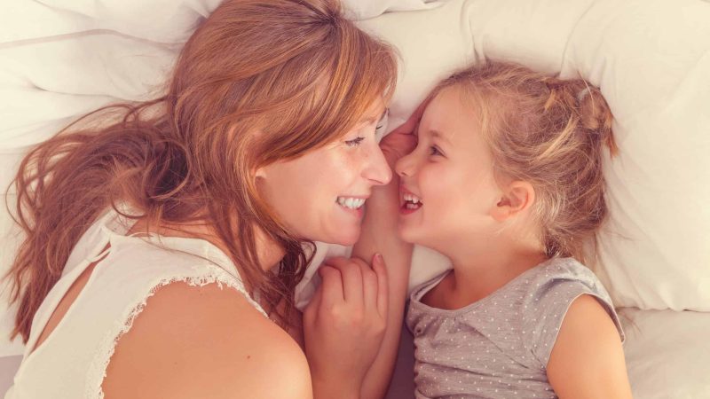 mother and daughter waking up with a smile