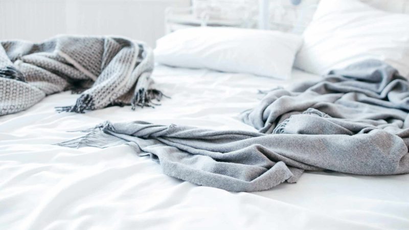 Sleep disorder, insomnia. Empty messy unmade bed. Cozy home textile in bedroom. Warmth and comfort.