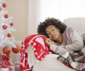 Woman sleeping on couch beside Christmas tree